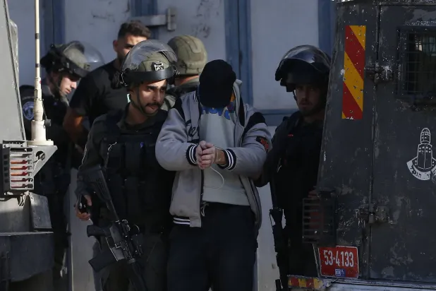 جنود إسرائيليون يعتقلون فلسطينياً من مخيم بلاطة في الضفة الغربية (إ.ب.أ)