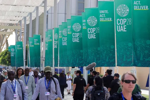 Participants walk next to COP28 flags in Expo City in Dubai (AFP)
