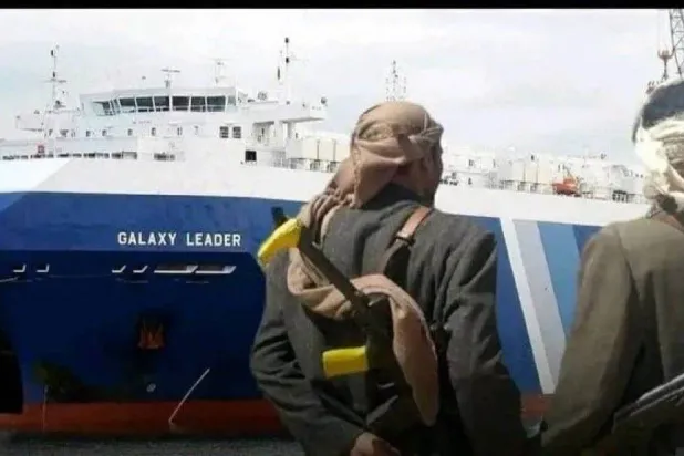 دو مسلح حوثی، عسکریت پسند گروپ کے ذریعے ہائی جیک کیے گئے بین الاقوامی جہاز "گلیکسی لیڈر" کے سامنے کھڑے ہیں (X)