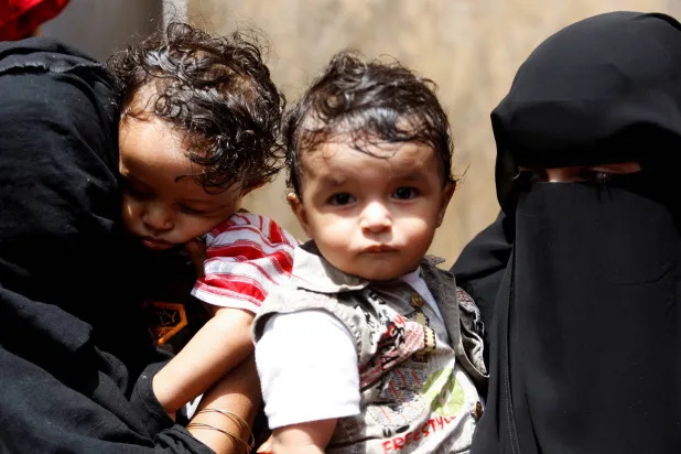 FILE PHOTO: Women hold their children as they wait outside a health center where they will receive nutritional support from the World Food Programme (WFP) June 9, 2010 in Yemen. REUTERS/Khaled Abdullah/File Photo