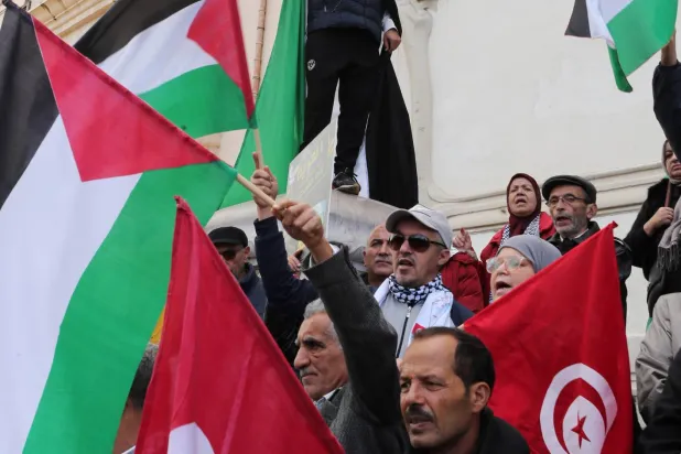 رفع العلمين التونسي والفلسطيني في التظاهرة (إ.ب.أ)