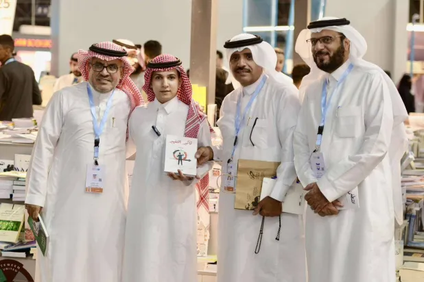 الدكتور فهد المالكي متوسطا مجموعة من الإعلاميين في معرض الكتاب بجدة (الشرق الأوسط)