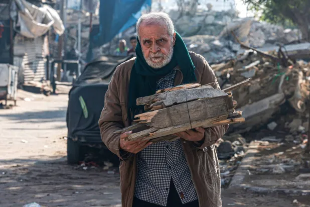 گزشتہ روز جنوبی غزہ کی پٹی کے شہر رفح میں ایک فلسطینی ایندھن میں استعمال کرنے کے لیے لکڑی اٹھائے لے جا رہا ہے (اے ایف پی)