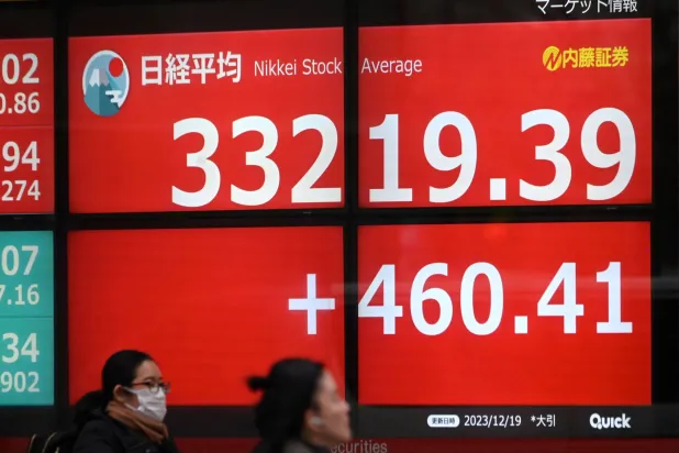 مشاة بجوار شاشة عملاقة تعرض تحركات الأسهم في بورصة اليابان وسط العاصمة طوكيو (أ.ف.ب)