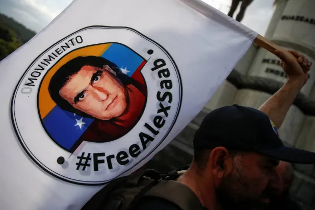 متظاهر من حركة «أطلقوا سراح أليكس صعب» يحمل لافتة في قافلة تطالب بالإفراج عن رجل الأعمال الكولومبي (أرشيفية- رويترز)