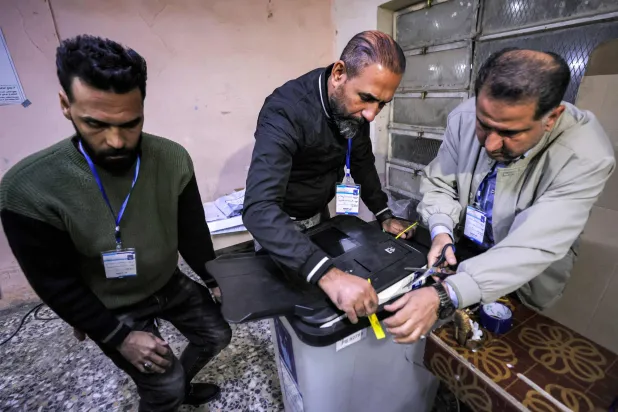 یک کارمند انتخاباتی نوار نتایج اولیه را از صندوق رای در بغداد، ۱۸ نوامبر بیرون می‌کشد (AFP)