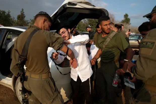 يهود أرثوذكس يساعدون جنوداً عائدين من معارك غزة على أداء الصلاة اليهودية يوم 14 ديسمبر الجاري (إ.ب.أ)