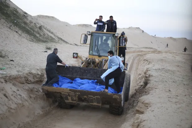 جرافة تحمل جثث الفلسطينيين الذين قُتلوا في شمال قطاع غزة وقام الجيش الإسرائيلي بتسليمهم خلال جنازة جماعية في رفح (أ.ب)