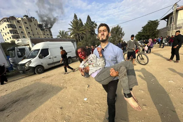 غزہ کی پٹی کے وسط پر اسرائیلی بمباری کے بعد ایک فلسطینی شخص زخمی بچی کو اٹھائے ہوئے ہے (اے پی)