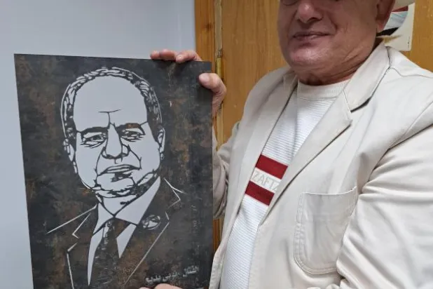 الفنان نوبي بديع مع لوحته التي حولها إلى بورتريه من الحديد للرئيس المصري عبد الفتاح السيسي