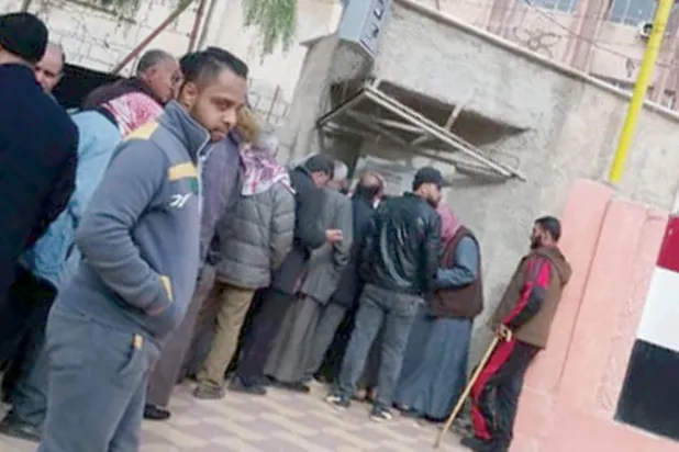 موظفون سوريون أمام صراف أحد البنوك لتسلم رواتبهم الشهرية في محافظة درعا (الشرق الأوسط)