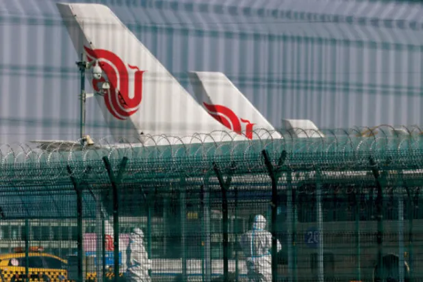 عاملون في مطار العاصمة بكين الدولي ويظهر مدى تشديد الاحترازات من كورونا (رويترز)