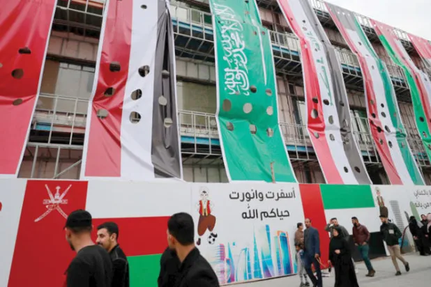 عراقيون يمرون قرب مبنى رُفعت عليه أعلام عملاقة للدول الخليجية في البصرة الخميس الماضي (أ.ف.ب)