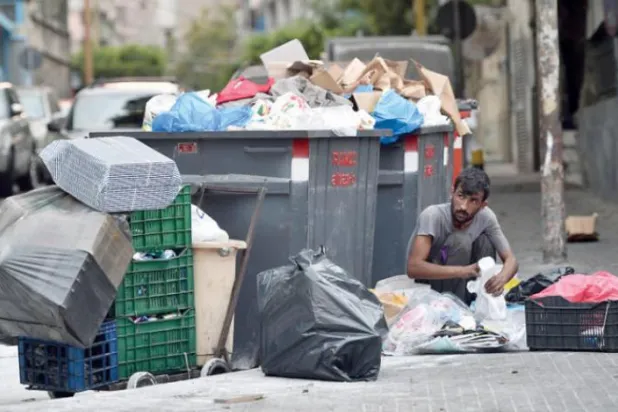 A Lebanese citizen searches in the garbage for what can be collected to sell and provide a source of livelihood for his family (EPA)
