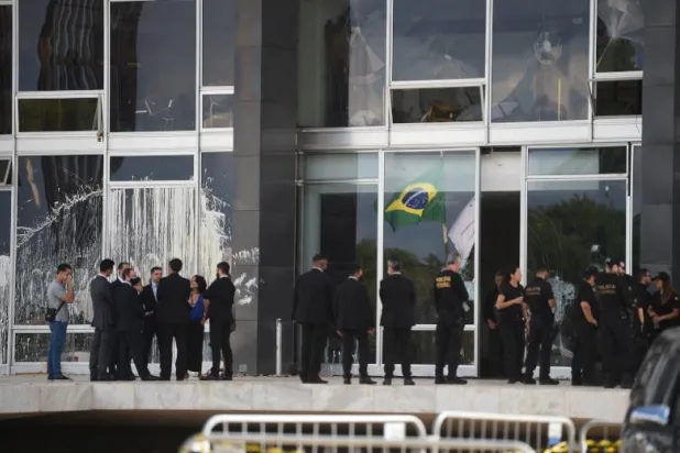 مسؤولون قضائيون وآخرون من الشرطة حارج مبنى المحكمة العليا المتضرر في برازيليا (أ.ف.ب)
