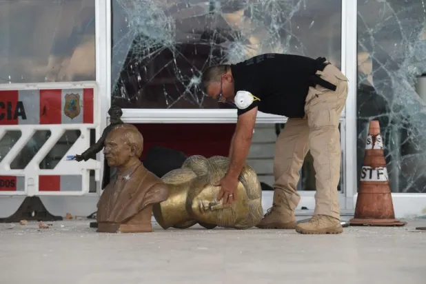 شرطي يجمع بعض الحطام من مبنى المحكمة العليا في برازيليا (أ.ف.ب)