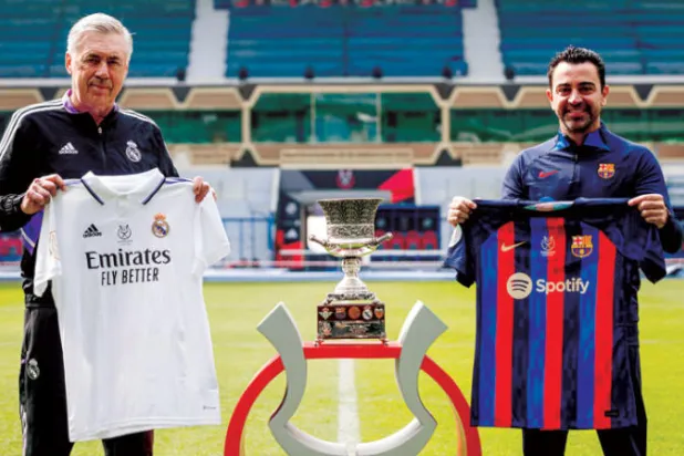 تشافي وأنشيلوتي يستعرضان قميصي فريقيهما وأمامهما كأس السوبر (إ.ب.أ)
