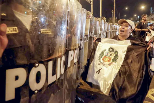 متظاهرون في مواجهة رجال أمن خلال احتجاج ضد الحكومة، في ليما (إ.ب.أ)