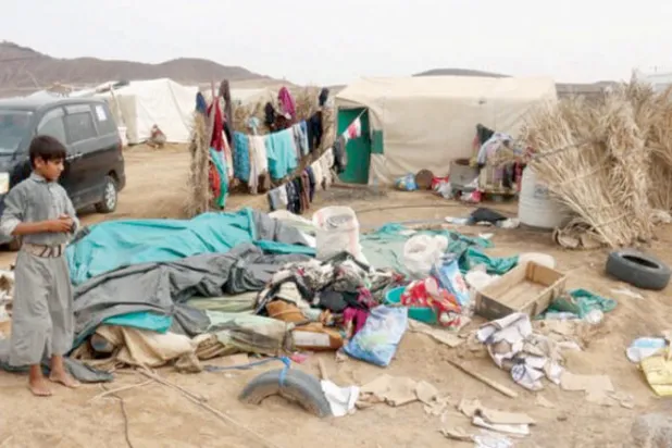 طفل يمني يتأمل ما تبقى من متعلقات أسرته بعد يوم ماطر في مخيم للنازحين في مأرب (رويترز)