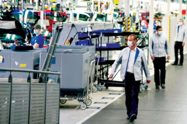 عمال مراقبة في مصنع لإنتاج آلات وماكينات ألمانية (رويترز)