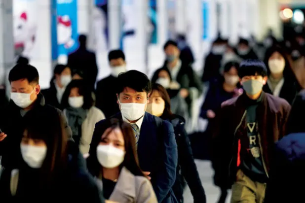 مشاة يعبرون أحد شوارع الحي المالي في العاصمة اليابانية طوكيو (إ.ب.أ)