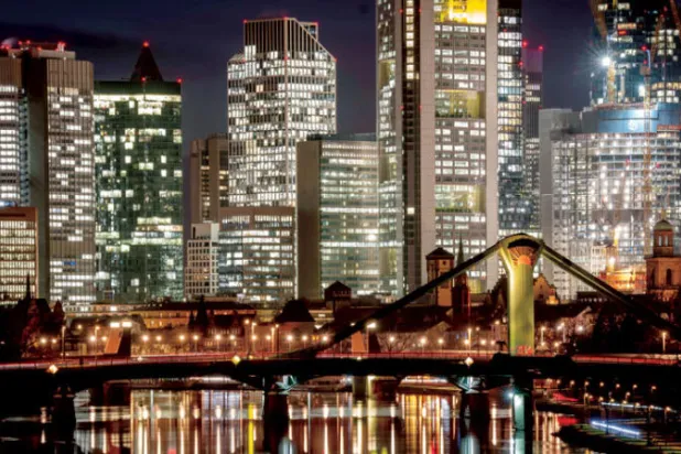 مبان وأبراج مضاءة بالحي المصرفي في نهر الماين بفرانكفورت (أ.ب)