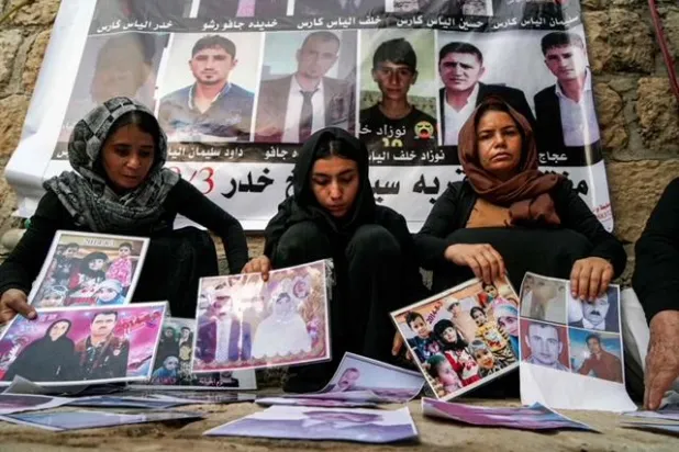 إيزيديات يعرضن صوراً لضحايا قتلهم تنظيم «داعش» الإرهابي (أ.ف.ب)