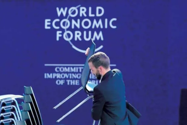 رجل يوضب الكراسي خلال تنظيف قاعة المؤتمر في دافوس، أمس (أ.ب)