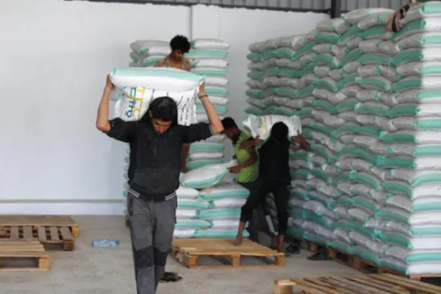 Workers carry bags of grain in a warehouse in Sanaa, amid a sharp rise in food prices (EPA)
