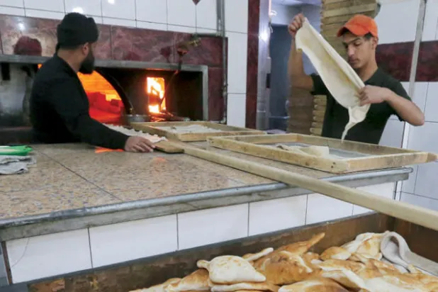 عاملان في مخبز للصمون في بغداد (أ.ف.ب)
