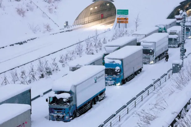 شاحنات عالقة بسبب الثلوج الكثيفة على طريق شين-ميشين السريع في اليابان أمس 25 يناير 2023 (أ.ف.ب)