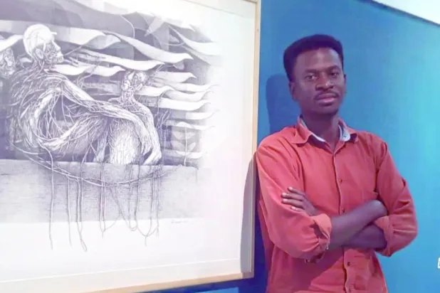 التشكيلي السوداني محمد عبد الرسول بجانب إحدى لوحاته