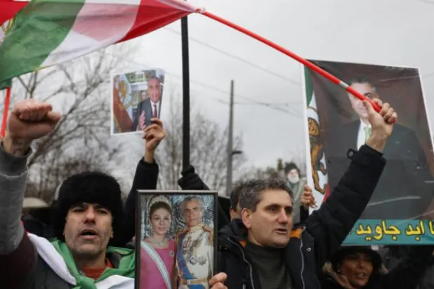 Eski İran şahının destekçileri, geçen hafta Strazburg’daki Avrupa Parlamentosu Genel Merkezi önünde düzenlenen muhalefet gösterisine katıldıkları sırada onun ve oğlunun fotoğrafını elinde tutarken (AP)