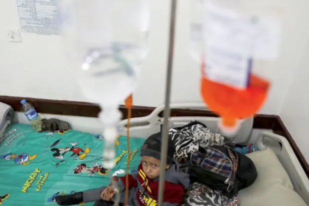 طفل يمني مريض بالسرطان ينظر وهو جالس على سرير في المركز الوطني للأورام في صنعاء (رويترز)