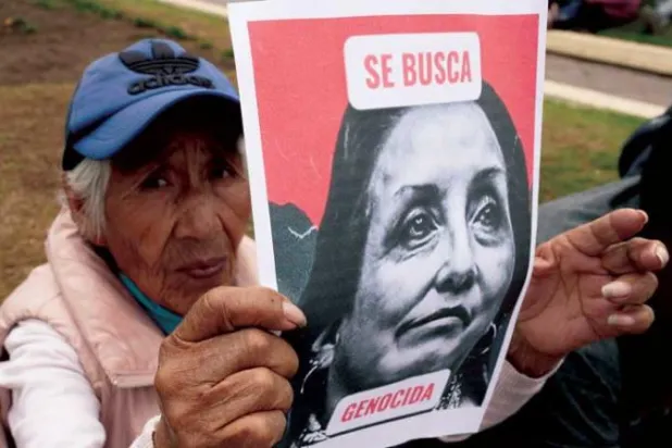 متظاهرة ضد الرئيسة دينا بولوارتي ترفع صورة لها مكتوباً عليها: مطلوبة للعدالة... أول من أمس (أ.ف.ب)