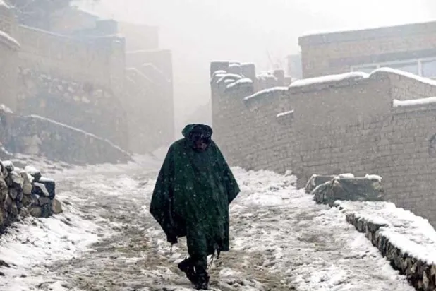 أفغاني يسير في شارع مغطى بالثلج في كابل (أ.ف.ب)