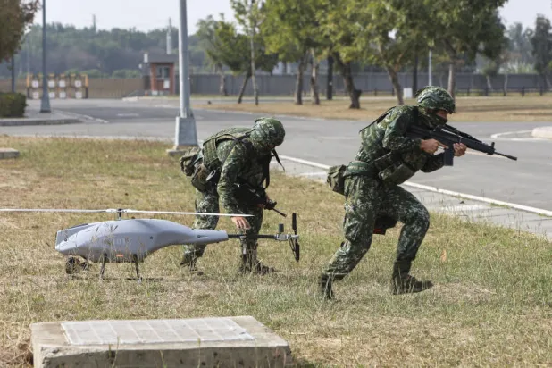 جنديان تايوانيان وقربهما طائرة مسيّرة خلال تدريب دفاعي (أ.ب)