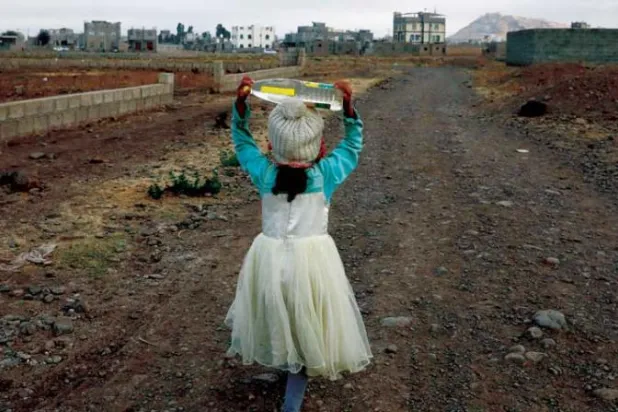 طفلة يمنية تساعد في جلب الماء لأسرتها بعد عودتها من المدرسة في ضواحي صنعاء (إ.ب.أ)