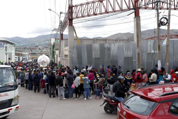 بيروفيون ينتظرون الحصول على غاز منزلي في مدينة كوسكو التي حصل فيها شح في المواد الاستهلاكية الرئيسية بسبب قطع المحتجين المناهضين للسلطة طرقاً عديدة (إ.ب.أ)