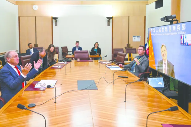 وزير التجارة الأسترالي دون فاريل يتحدث إلى نظيره الصيني وانغ وينتاو عبر زووم أمس (أ.ب)