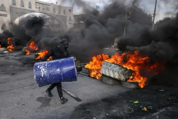فلسطينيون يحرقون إطارات لقطع الطريق المؤدية إلى أريحا الإثنين بعد مداهمة القوات الإسرائيلية البلدة. (إ.ف.ب)