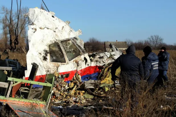 عمال محليون ينقلون قطعة من حطام طائرة الرحلة الماليزية «MH 17» في نوفمبر 2014 بمنطقة دونيتسك شرق أوكرانيا (رويترز)
