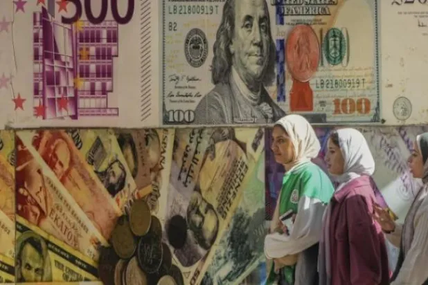 فتيات مصريات يعبرن أمام إحدى شركات الصرافة في القاهرة (أ.ب)