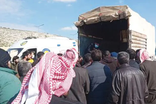 ينتظرون إنزال جثامين من شاحنة عند معبر باب الهوى (الشرق الأوسط)