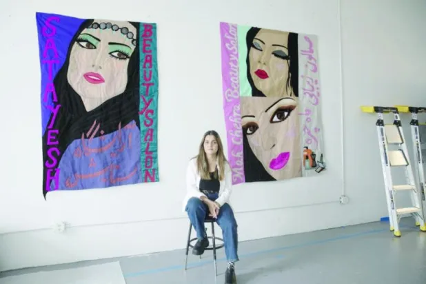 الفنانة هانغاما أميري مع اثنين من أعمالها (نيويورك تايمز)
