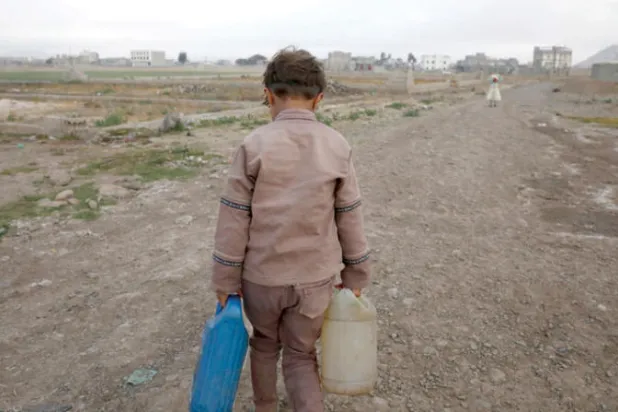 طفل يمني يجلب الماء لأسرته قبل ذهابه للمدرسة في ضواحي صنعاء (إ.ب.أ)