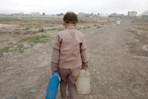 Yemenli çocuk, Sana'daki bir banliyöde okula gitmeden önce ailesi için su taşıyor (EPA)