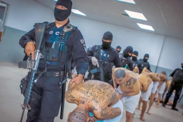 رجال أمن يرافقون سجناء لدى وصولهم إلى سجن «تيكولوكو» (أ.ف.ب)