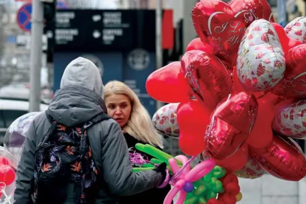 أوكراني يبيع بالونات في عيد الحب وسط العاصمة كييف (أ.ف.ب)