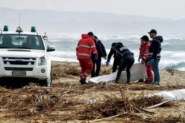 عمال إنقاذ يجمعون جثث المهاجرين من شاطئ كالابريا (رويترز)
